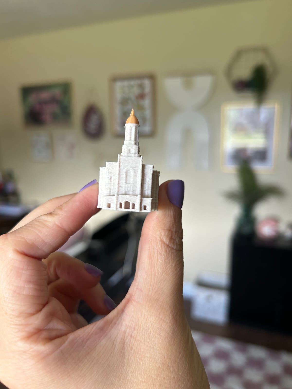 Tiny 2in Smithfield Utah Temple statue held between two fingers, front view with gold dome