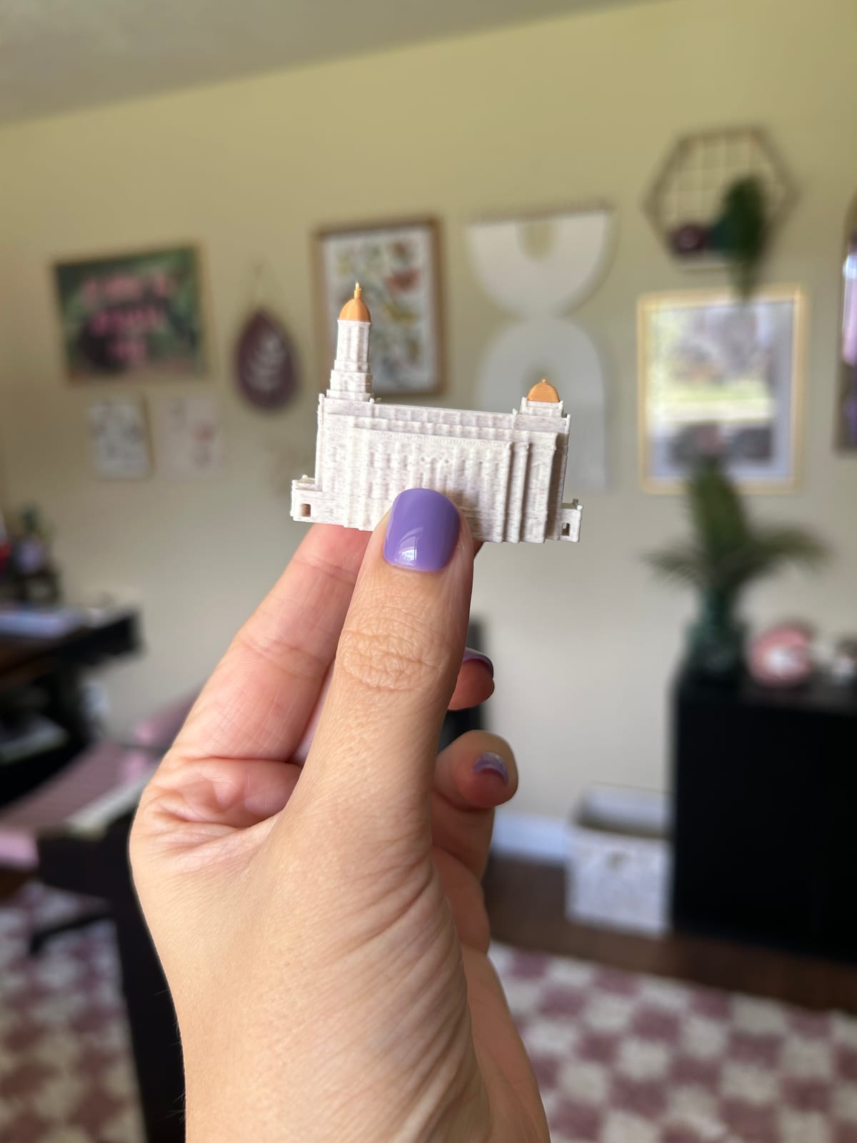 Tiny 2in Smithfield Utah Temple statue held up in one hand, side view